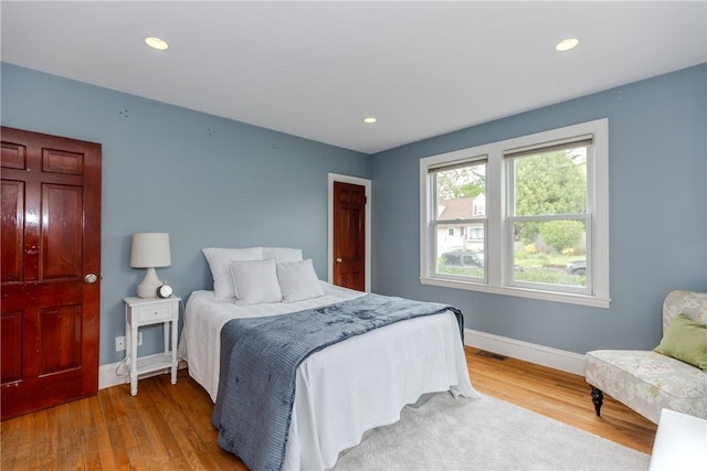 bedroom with baseboards, wood finished floors, and recessed lighting