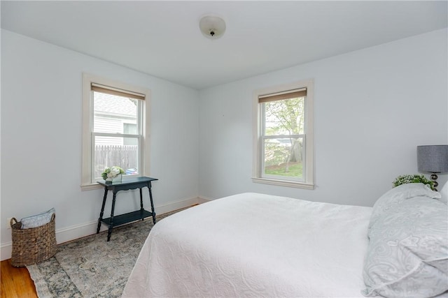 bedroom featuring multiple windows, baseboards, and wood finished floors