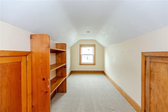 additional living space featuring light colored carpet, lofted ceiling, and baseboards