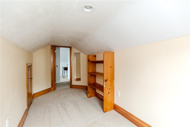 additional living space with light carpet, lofted ceiling, and baseboards