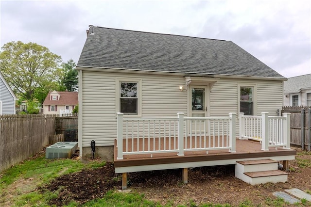 back of property with fence, central AC unit, a wooden deck, and roof with shingles