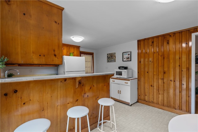 11 Cedar Ave, Middletown, RI 02842 - kitchen featuring white appliances, light flooring, a kitchen bar, light countertops, and brown cabinets