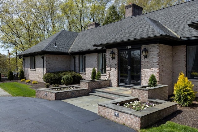 136 White Birch Cir, Scituate, RI 02831 - view of front of home featuring french doors, a chimney, a shingled roof, and brick siding
