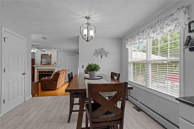 14 Ginger Trl, Coventry, RI 02816 - dining room with light wood-style floors, a tiled fireplace, a baseboard radiator, and a ceiling fan
