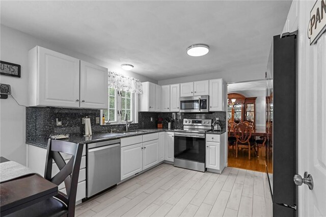 14 Ginger Trl, Coventry, RI 02816 - kitchen featuring stainless steel appliances, a sink, dark countertops, decorative backsplash, and white cabinetry