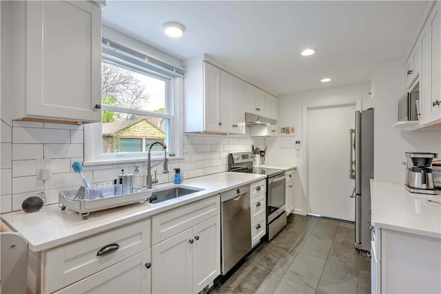 kitchen with stainless steel appliances, range hood, a sink, white cabinetry, and decorative backsplash