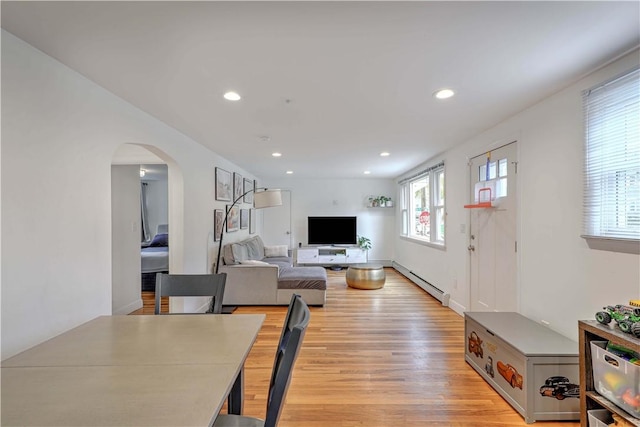 living area featuring light wood finished floors, a baseboard heating unit, arched walkways, and recessed lighting