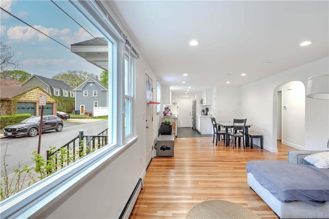 living area with healthy amount of natural light, arched walkways, light wood-style flooring, and recessed lighting