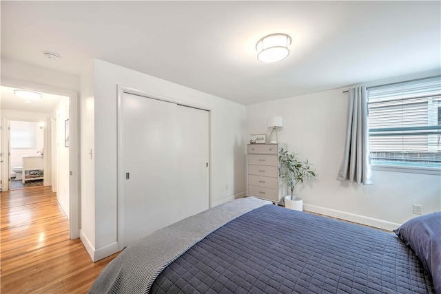 bedroom featuring baseboards, light wood-type flooring, and a closet