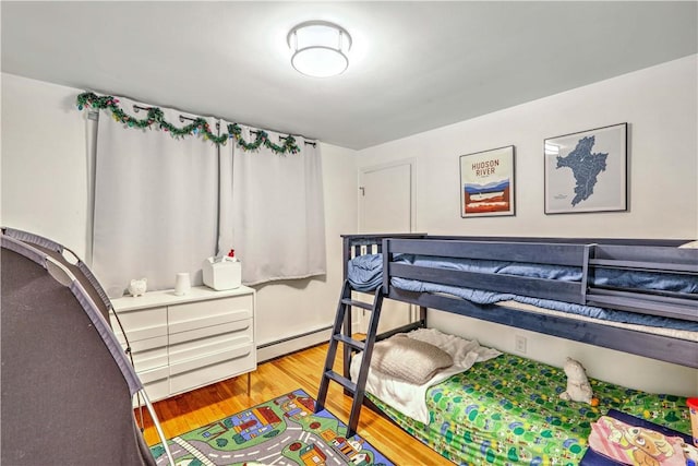 bedroom featuring light wood-type flooring and a baseboard heating unit