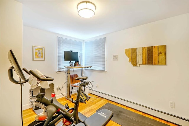 exercise area featuring baseboard heating, wood finished floors, and baseboards