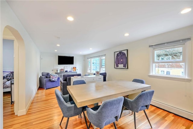 dining area with a baseboard heating unit, light wood-style flooring, arched walkways, recessed lighting, and baseboards