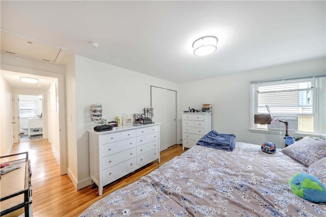 bedroom featuring multiple windows, light wood finished floors, and a closet