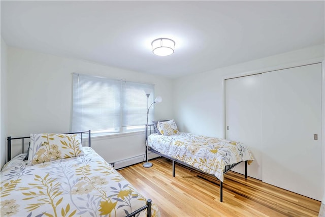 bedroom featuring wood finished floors, a closet, and a baseboard radiator