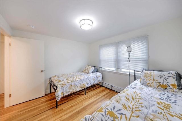 bedroom with a baseboard heating unit and wood finished floors