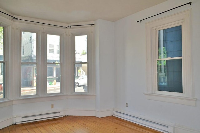 spare room featuring a baseboard radiator, healthy amount of natural light, and light wood-style flooring