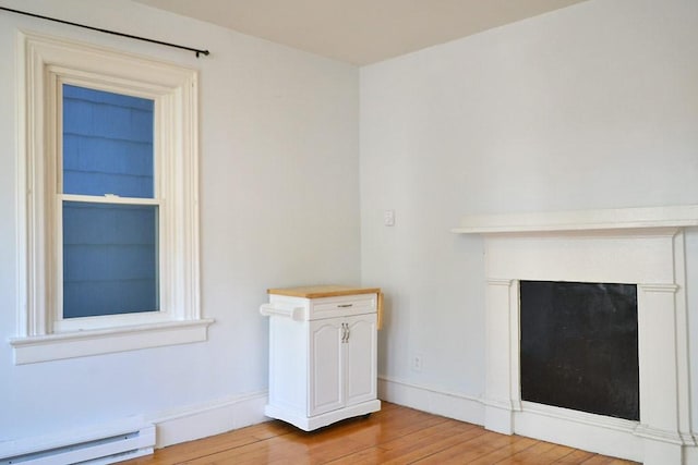 detailed view of baseboard heating, wood finished floors, baseboards, and a fireplace