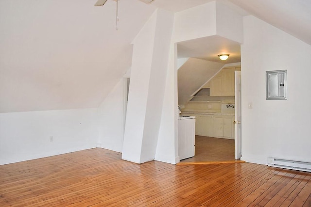additional living space with lofted ceiling, electric panel, light wood finished floors, a baseboard radiator, and a ceiling fan