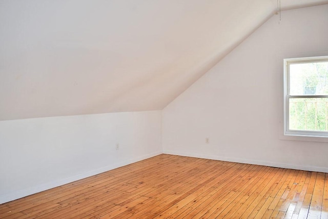 additional living space featuring vaulted ceiling, light wood finished floors, and baseboards