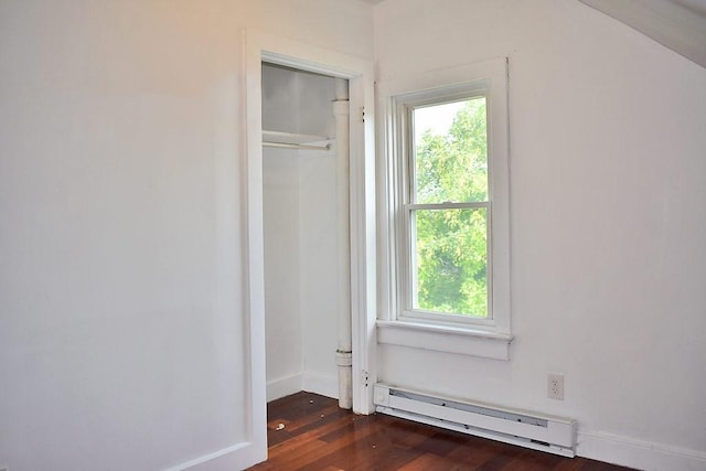 unfurnished bedroom with baseboard heating, multiple windows, dark wood-style flooring, and a closet