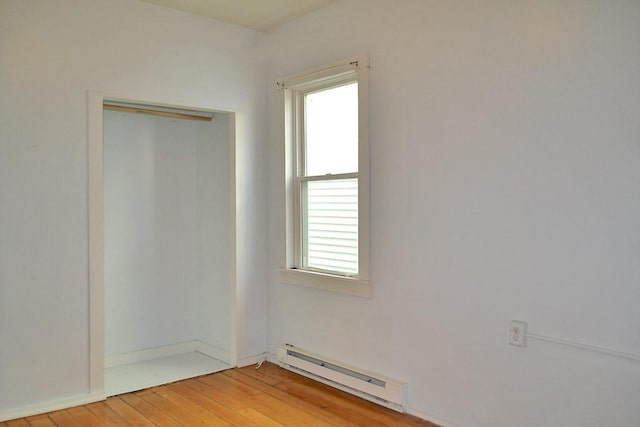 unfurnished room with a baseboard radiator, plenty of natural light, and light wood finished floors