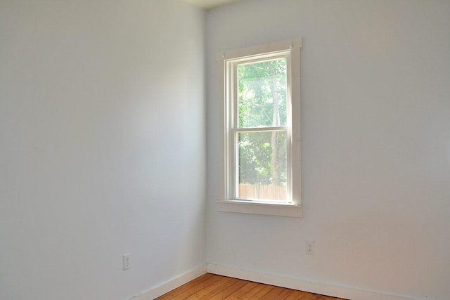 spare room featuring plenty of natural light, baseboards, and light wood-type flooring