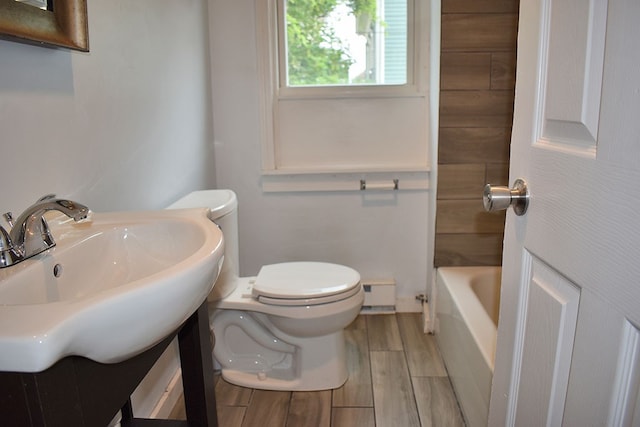 bathroom with toilet, wood finished floors, a tub, and vanity