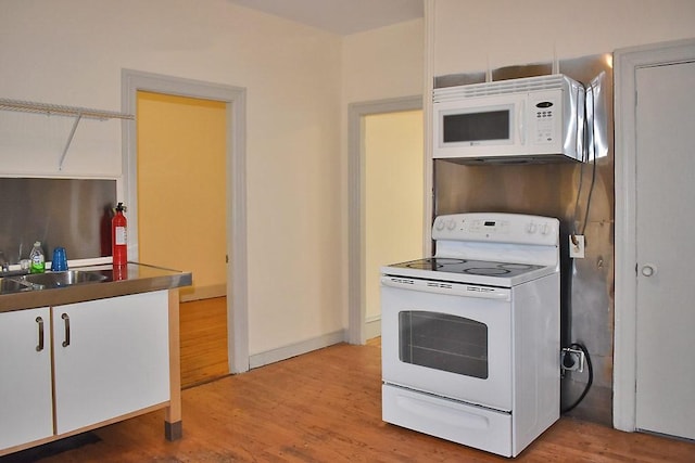 kitchen with white appliances, light wood finished floors, and a sink