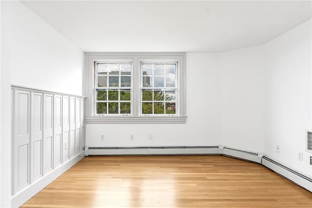 spare room featuring light wood-style flooring and baseboard heating