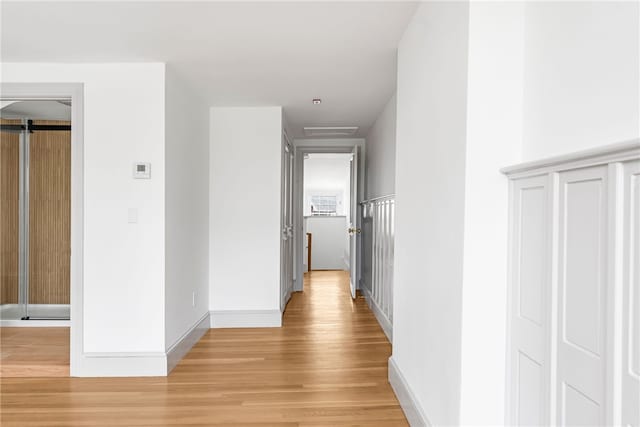 hall featuring light wood finished floors and baseboards