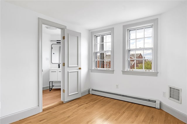 unfurnished bedroom with a baseboard radiator, light wood finished floors, and a sink