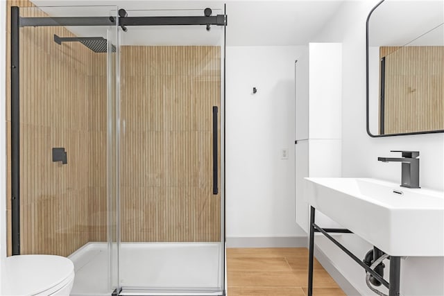 bathroom featuring a stall shower, toilet, wood finished floors, and baseboards