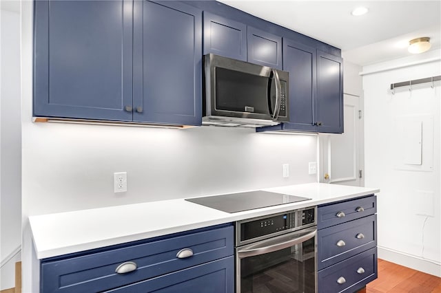 kitchen with stainless steel appliances, blue cabinetry, light countertops, and recessed lighting