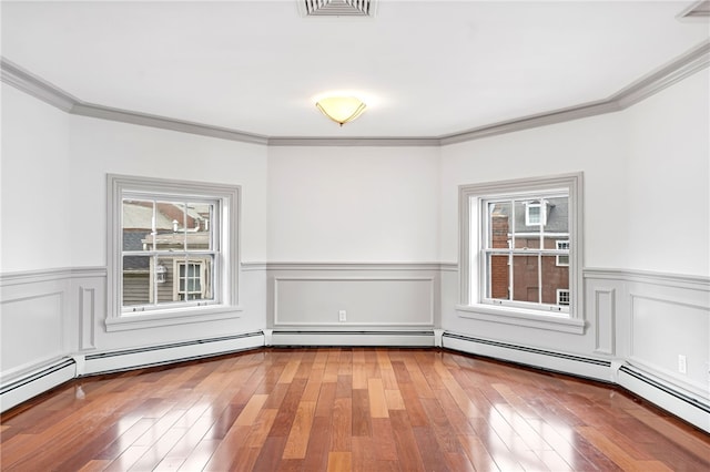 unfurnished room featuring healthy amount of natural light, ornamental molding, wainscoting, and hardwood / wood-style floors