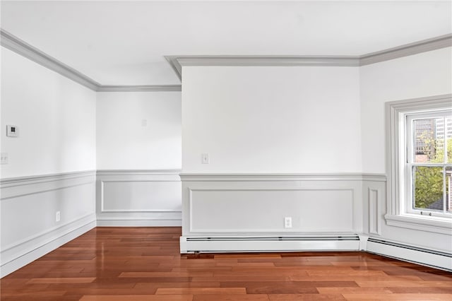 unfurnished room featuring crown molding, wainscoting, and wood finished floors