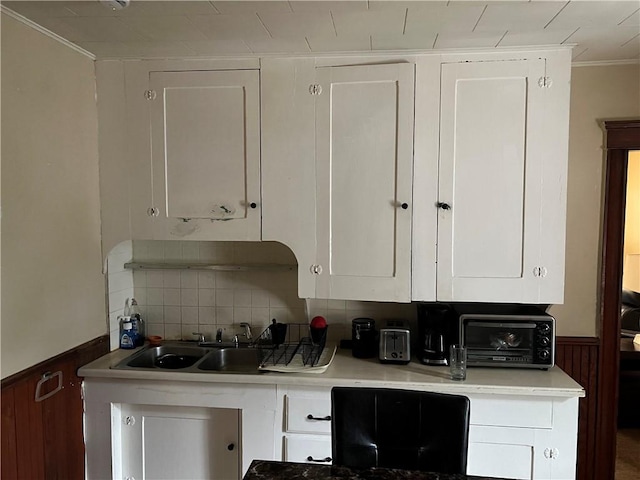 243 Transit St, Woonsocket, RI 02895 - kitchen with white cabinets, crown molding, a wainscoted wall, tasteful backsplash, and light countertops
