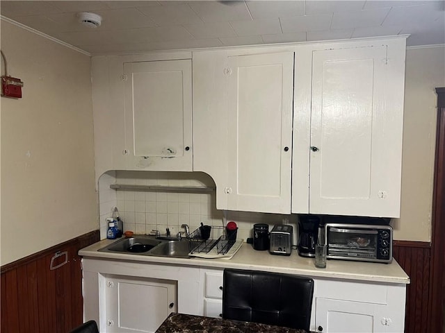 243 Transit St, Woonsocket, RI 02895 - kitchen featuring a wainscoted wall, white cabinetry, a sink, light countertops, and wood walls