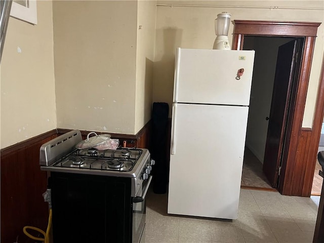 243 Transit St, Woonsocket, RI 02895 - kitchen featuring gas range oven, freestanding refrigerator, a wainscoted wall, and wood walls