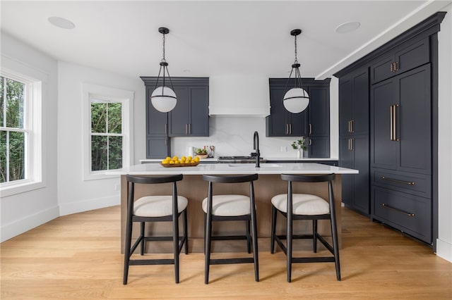 104 Second St, Newport, RI 02840 - kitchen featuring a sink, light countertops, a kitchen bar, light wood-style flooring, and decorative light fixtures