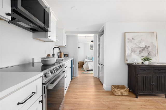 104 Second St, Newport, RI 02840 - kitchen featuring appliances with stainless steel finishes, light wood-style floors, a sink, white cabinets, and light countertops