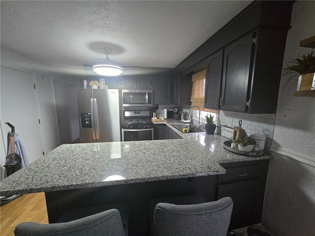 59 Columbus Ave, North Providence, RI 02911 - kitchen featuring stainless steel appliances, a sink, a breakfast bar, a peninsula, and light stone counters