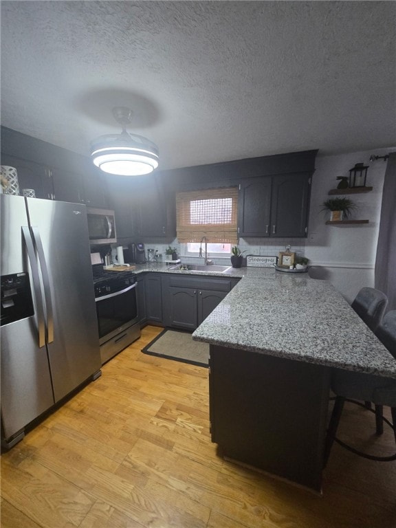59 Columbus Ave, North Providence, RI 02911 - kitchen featuring stainless steel appliances, a sink, a peninsula, a kitchen bar, and light wood finished floors