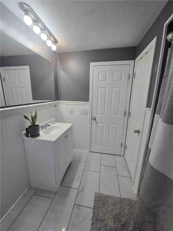 59 Columbus Ave, North Providence, RI 02911 - bathroom with marble finish flooring, vanity, a textured ceiling, and wainscoting