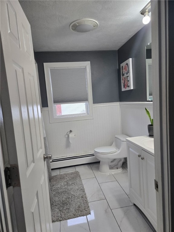 59 Columbus Ave, North Providence, RI 02911 - half bathroom with a wainscoted wall, a baseboard radiator, toilet, vanity, and a textured ceiling