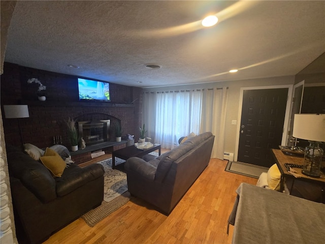 59 Columbus Ave, North Providence, RI 02911 - living area featuring a baseboard radiator, light wood-style flooring, a brick fireplace, and a textured ceiling