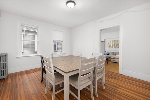 dining space featuring radiator heating unit, wood-type flooring, and baseboards