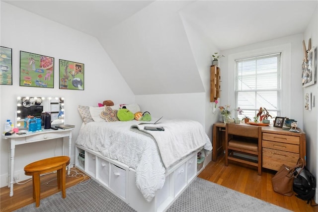 bedroom featuring lofted ceiling, wood finished floors, and an office area