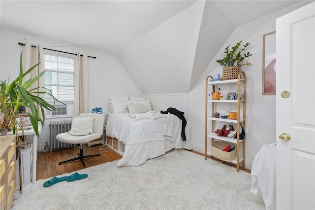 bedroom featuring radiator heating unit, wood finished floors, and lofted ceiling