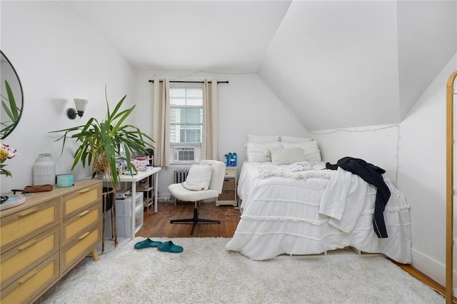 bedroom with wood finished floors, vaulted ceiling, and cooling unit