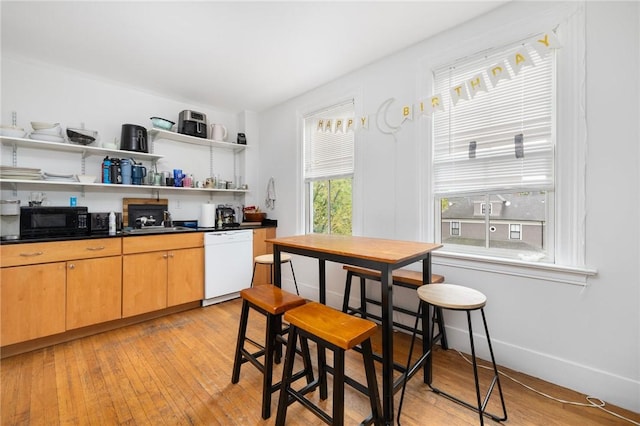 kitchen featuring white dishwasher, black microwave, dark countertops, and a sink